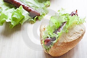 Hot dog. Grilled hot dogs with fresh salad lettuce on wooden table.