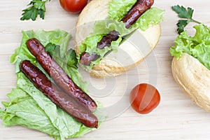 Hot dog. Grilled hot dogs with fresh salad lettuce on wooden table.