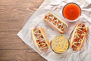 Hot dog with grilled sausage  mustard  and ketchup  onions  and greens on paper background