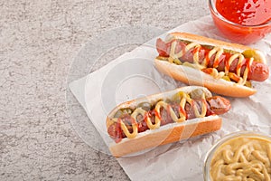 Hot dog with grilled sausage  mustard  and ketchup  onions  and greens on paper background