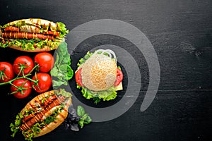 Hot dog and hamburger with cheese, meat and greens on Wooden background.