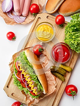 Hot dog with ketchup and mustard on a white table. Ingredients for cooking hot dogs. View from above