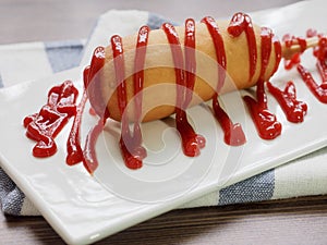 Hot dog with ketchup on a white plate