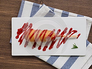 Hot dog with ketchup on a white plate