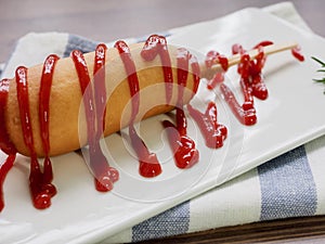 Hot dog with ketchup on a white plate