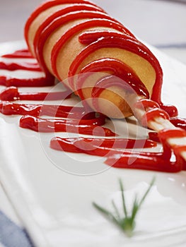 Hot dog with ketchup on a white plate