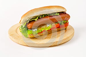 Hot dog lying on a round wooden board on a white background