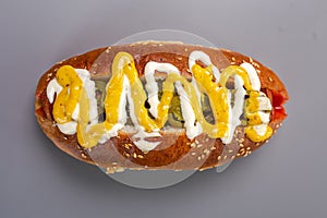 Hot dog sausage in a bun with sauces, isolated on a gray background