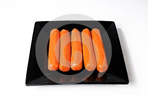 Hot dog sausages on black plate on a white background