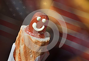 A hot dog with a smile and ketchup in a close-up against the American flag