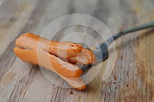 Hot dog stab in fork on wooden board