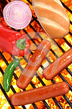 Hot dogs, bun and veggies on a barbecue grill