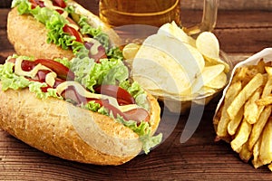 Hot dogs with glass of beer with crisps,french fries on wooden b photo