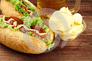 Hot dogs with glass of beer with crisps on wooden board photo