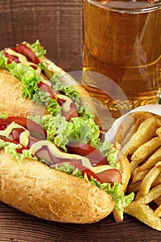 Hot dogs with glass of beer with french fries on wooden board photo