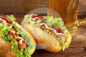 Hot dogs with glass of beer on wooden board photo