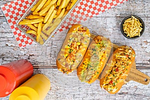 Hot dogs, french fries, and ketchup and mustard sauce jars on old wooden background. Top view