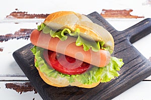 Hot dogs on a wooden Board. Hot dog with lettuce tomato and sausage. Copy space