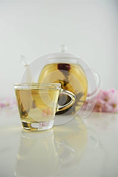 Drink of flowering tea in glass teapot with cup