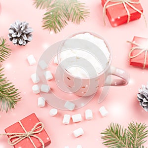 Hot drink with marshmallows close up. Christmas background with fir branches, lights, presents, pink decorations on pink
