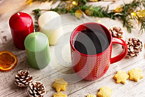 hot drink in red cup next to cookies and candles on the table. winter holidays, Christmas, New Year