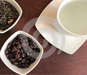 Hot drinks green tea leaf and black coffee beans , white Cup with hot water on a brown background of wooden table Breakfast