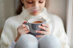 Girl with cacao mug looking at home window