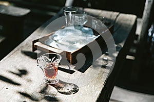 Hot drip coffee in drinking glass on wooden table with harsh sunlight