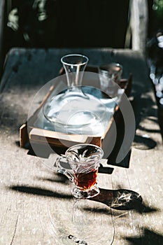 Hot drip coffee in drinking glass on wooden table with harsh sunlight