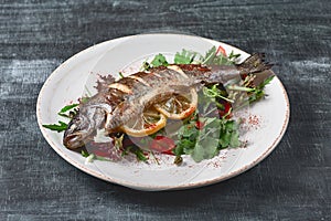 Hot fresh delicious roasted whole trout barbecue with fresh herbs and lemon, on a wooden background close-up