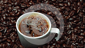 Hot fresh espresso was poured in white cup with pile of coffee bean. Comestible.