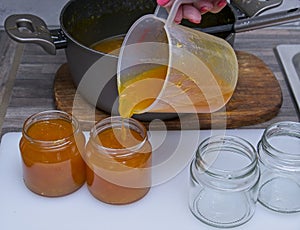 Hot freshly cooked apricot jam being poured into glass jars