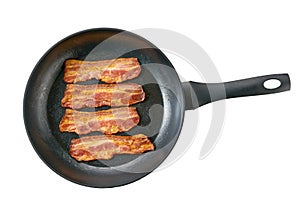 Hot fried bacon pieces in a skillet isolated on white background, top view. Macro photo of bacon being fried in a pan