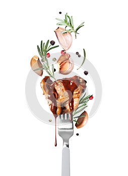 Hot fried beef steak on a fork with rosemary and garlic close up isolated on a white background