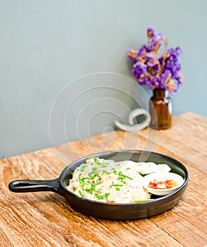 Hot fried rice on wooden table serve on black pan