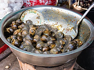 Hot fried snails selling on a street market in Cambodia