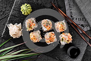 Hot fried Sushi rolls and maki set with smoked eel, cream cheese, avocado, caviar and wasabi on black slate background.