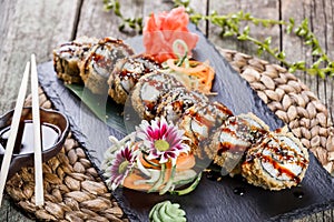 Hot fried Sushi rolls and maki set with smoked eel, cream cheese, avocado and wasabi on black stone on bamboo mat, selective focus