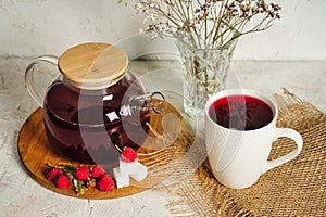 Hot fruit berry tea in glass teapot and cup with red antioxidant beverage, good morning concept