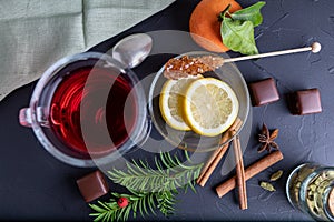 Hot fruit tea with lemon on the dark surface, top view