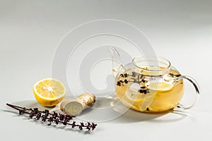 Hot ginger tea with lemon and honey in a glass cup on light grey background