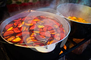 Hot gluhwein or mulled wine in a cauldron at fair, local treat, warm and spicy. A hot wholesome traditional citrus drink on fair.