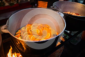 Hot gluhwein or mulled wine in a cauldron at fair, local treat, warm and spicy. A hot wholesome traditional citrus drink on fair.