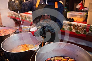 Hot gluhwein or mulled wine in a cauldron at fair, local treat, warm and spicy. A hot wholesome traditional citrus drink on fair.