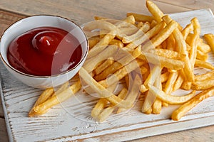 Hot golden french fries with ketchup on a wooden background. Tasty american fast food