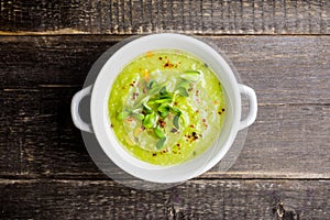 Hot green peas soup on the rustic background