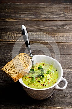 Hot green peas soup on the rustic background