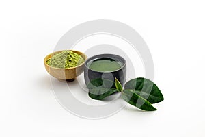 Hot green tea latte in black ceramic bowl on white background. Place with deep Green tea leaves out side.