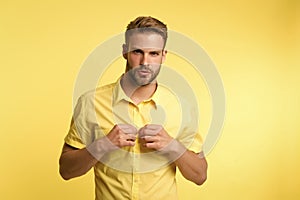 It is hot here. I will show you my sexy body. Man handsome bearded guy undressing yellow background. Guy confident