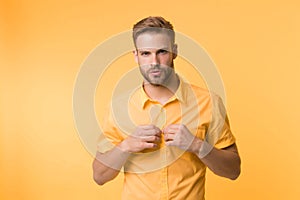 It is hot here. I will show you my sexy body. Man handsome bearded guy undressing yellow background. Guy confident